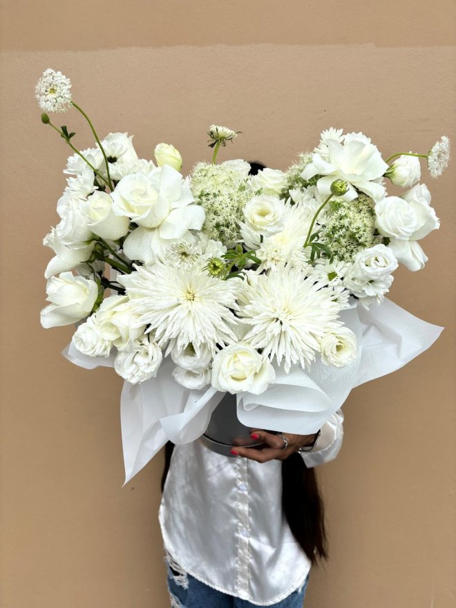 A white hatbox bouquet featuring roses, lisianthuses, and chrysanthemums.