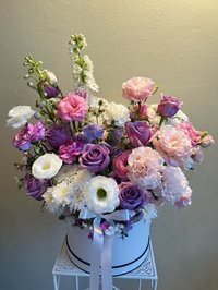 Bouquet with purple roses, pink carnations, and white lilies in a white round box