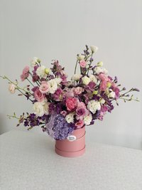 Pink, white, and purple flower bouquet with roses, lilies, and orchids in a round pink box