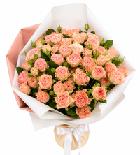 Peach rose bouquet wrapped in white and peach paper with green foliage