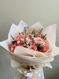 Bouquet of pink and white roses with greenery in elegant wrapping