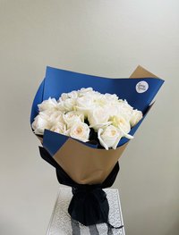 Bouquet of white roses wrapped in blue and brown paper.