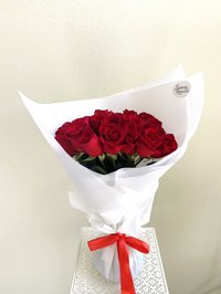 Bouquet of red roses wrapped in white paper with a red ribbon