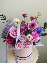 Pink and white bouquet with roses, lilies, and orchids in a round box
