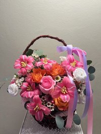 Basket of pink lilies, orange and pink roses, and white flowers with ribbons