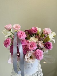 Pink, white, and purple Lisianthus bouquet with roses and lilies in a decorative container