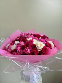 Pink, white, and red rose bouquet wrapped in pink paper with a ribbon
