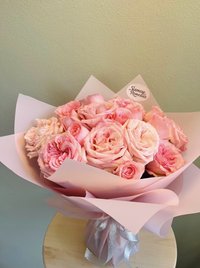 Bouquet of pink roses wrapped in soft pink paper with a silver ribbon