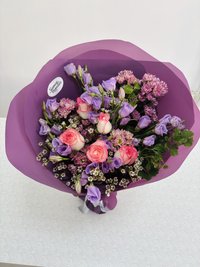 Lavender Bliss bouquet featuring pink and white roses, purple lilies, and orchids wrapped in purple paper