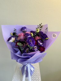 Lavender and pink bouquet with roses, lisianthus, and orchids wrapped in lavender paper