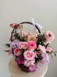 Pink, white, and purple flower bouquet with roses, lilies, and orchids in a decorative basket
