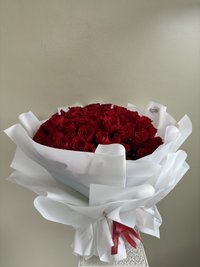 A bouquet of 101 red roses wrapped in elegant white paper.