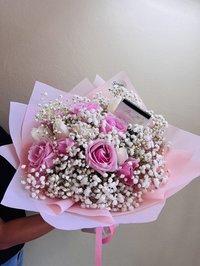 Bouquet of pink roses and baby's breath wrapped in pink paper