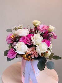 Pink and white bouquet with roses and lilies in a decorative container