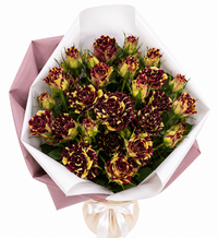 Bouquet of burgundy and yellow roses wrapped in pink and white paper with a satin ribbon