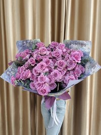 A large bouquet of vibrant purple roses wrapped in decorative paper with a purple ribbon.