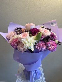 Lavender-wrapped bouquet with pink roses, white lilies, and purple orchids
