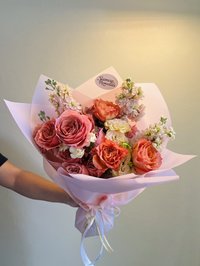 Pink and white rose and orchid bouquet with delicate wrapping in a pastel hue