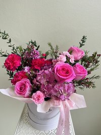 Pink and purple flower bouquet with roses, lilies, and orchids in a decorative white box