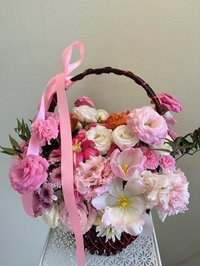 Basket of pink and white roses, lilies, and carnations with a pink ribbon
