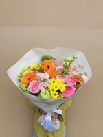 A vibrant bouquet of pink roses, orange gerberas, and yellow daisies wrapped in white paper.